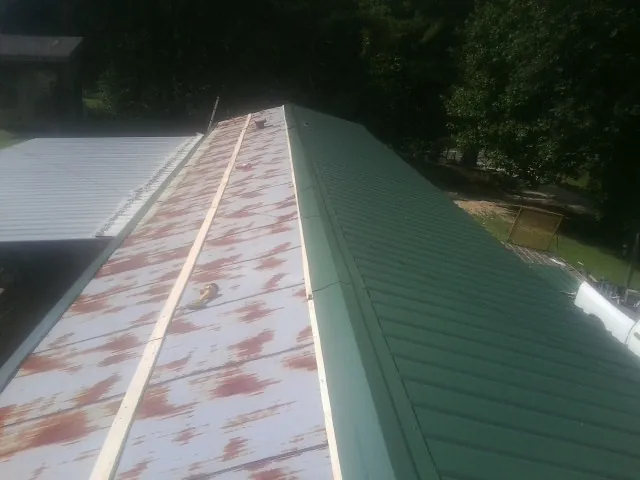 Old rusted panels beside newly installed green metal roofing — Wind Damage Roof Repair by Roofing Brothers in Walkersville
