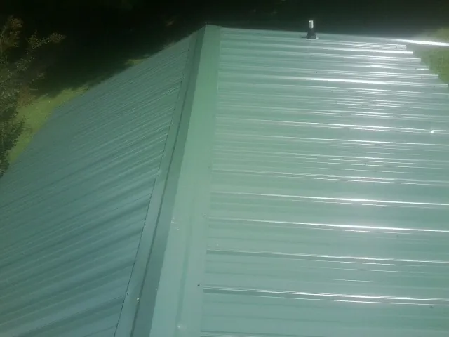 New green metal panels meeting at the ridge of a roof — Flat Roof Repair work by our crew in Walkersville